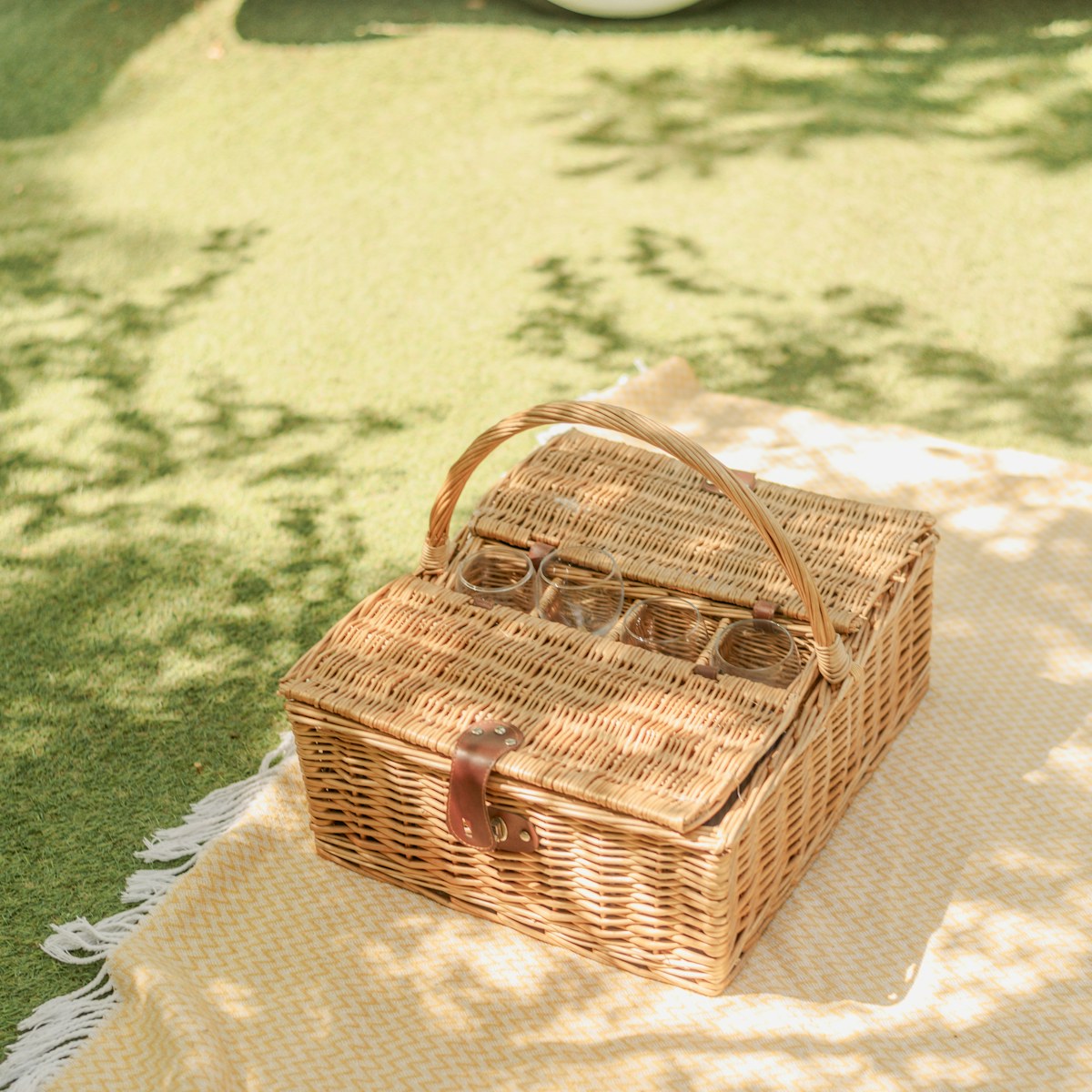 Large wicker picnic hamper with glass holders on a blanket