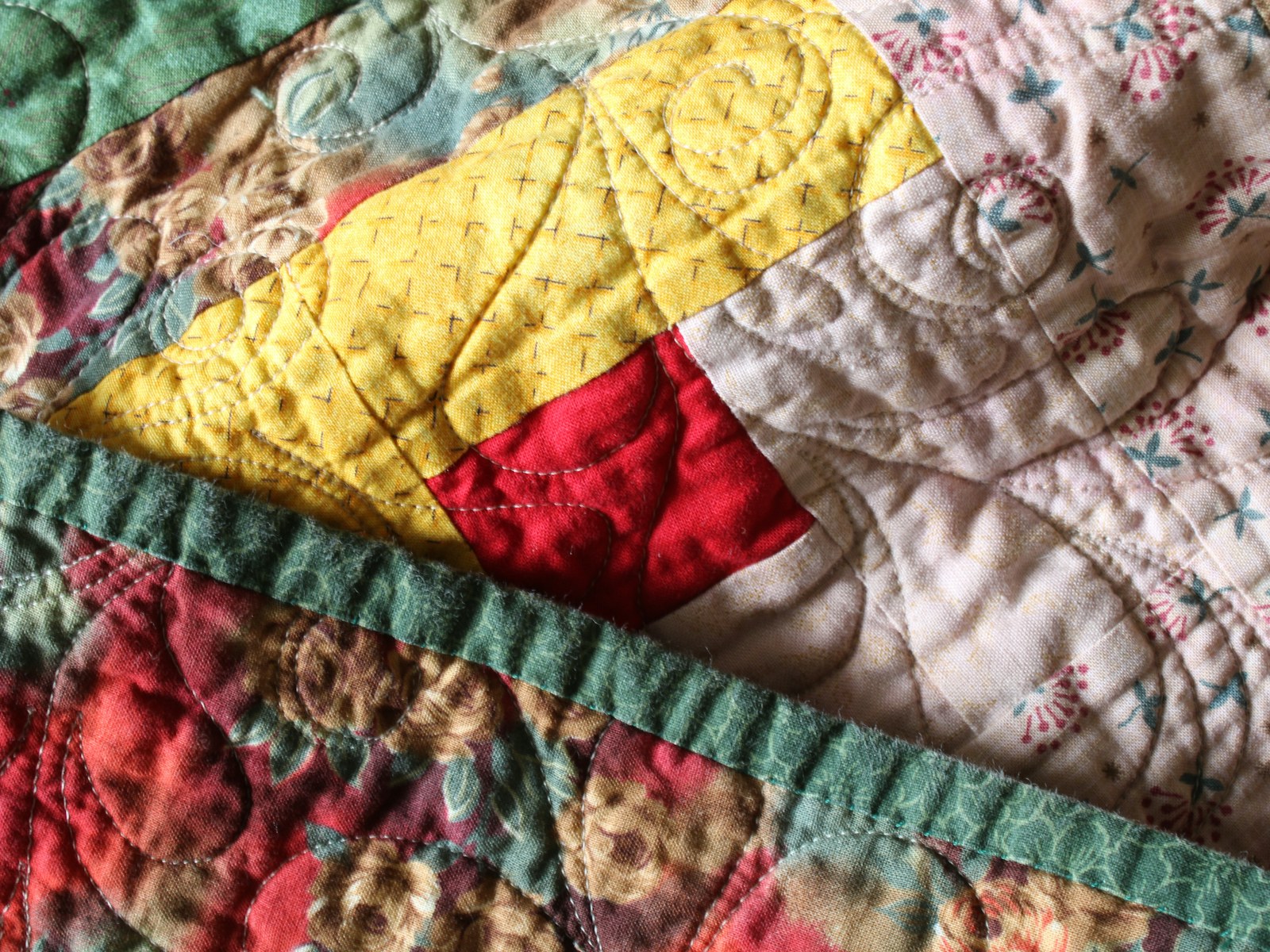 Close-up floral patchwork quilt in green, yellow and berry