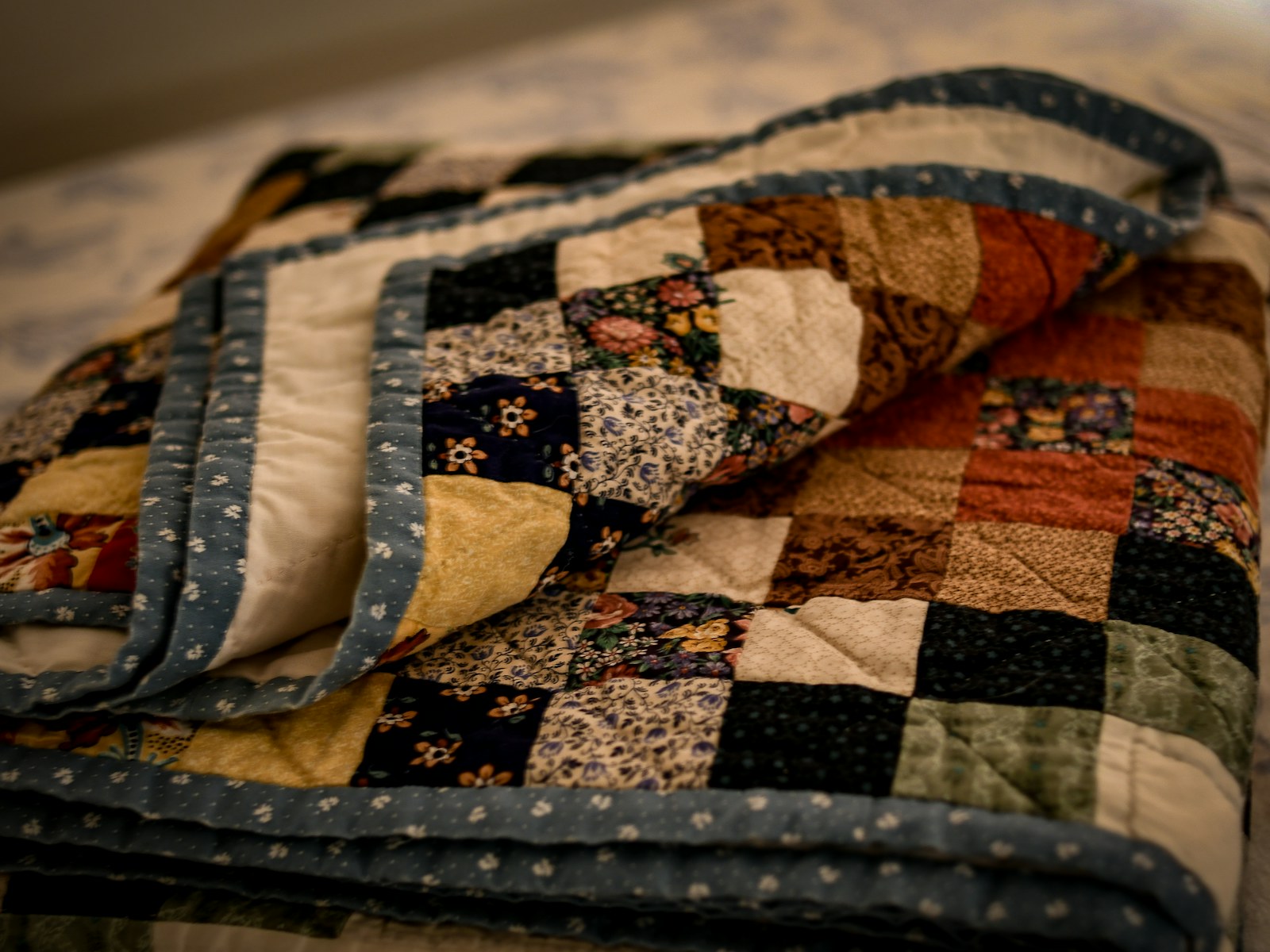 Folded heritage patchwork quilt in navy, cream, rust and sage